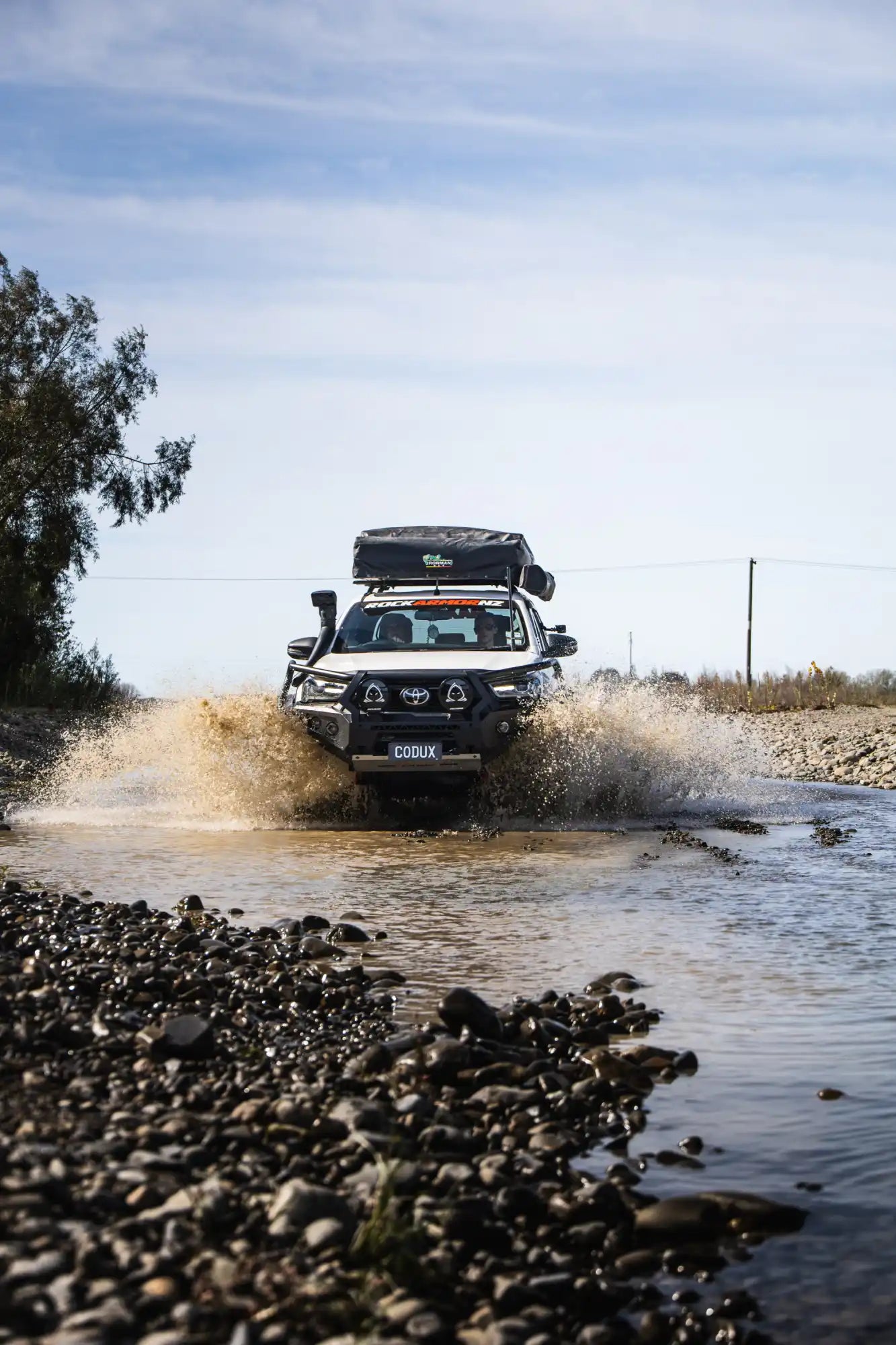 White off-road truck wading through water.