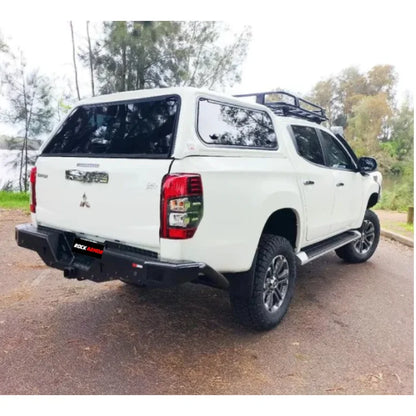 White Mitsubishi pickup truck rear fitted with rockarmor elite rear steel checker plate step and high lift jack mount