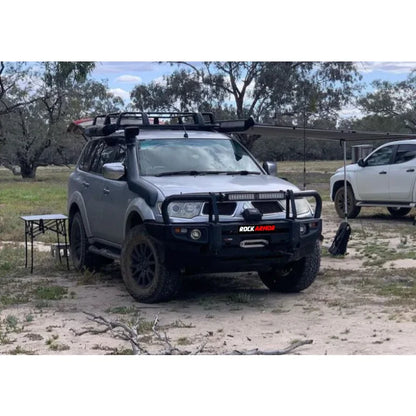 Silver mitsubishi triton challenger with rockarmor premium steel bullbar featuring led fog lights and roof rack