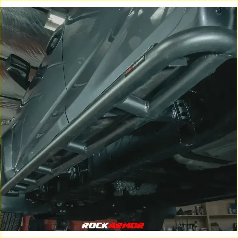 Black metal rock guard with rugged tubular design and visible welds for Toyota Landcruiser Fj100 and Lexus rock pack