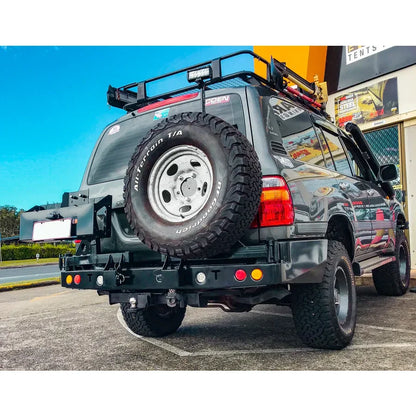 Gray rockarmor steel dual wheel carrier mounted on the rear of a toyota landcruiser fj105 off-road vehicle