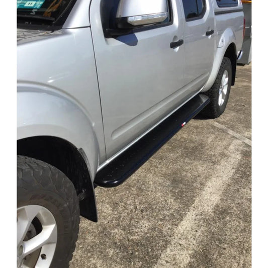 Silver Nissan Navara D40 pickup with black rockslider steel checker plate running board side steps shown from the back side