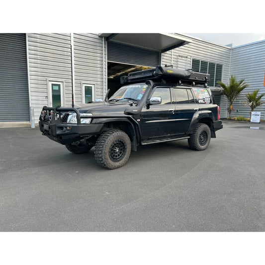 Black off-road vehicle with roof tent featuring rockarmor steel rockslider side steps for nissan patrol y61 gu1 and gu4