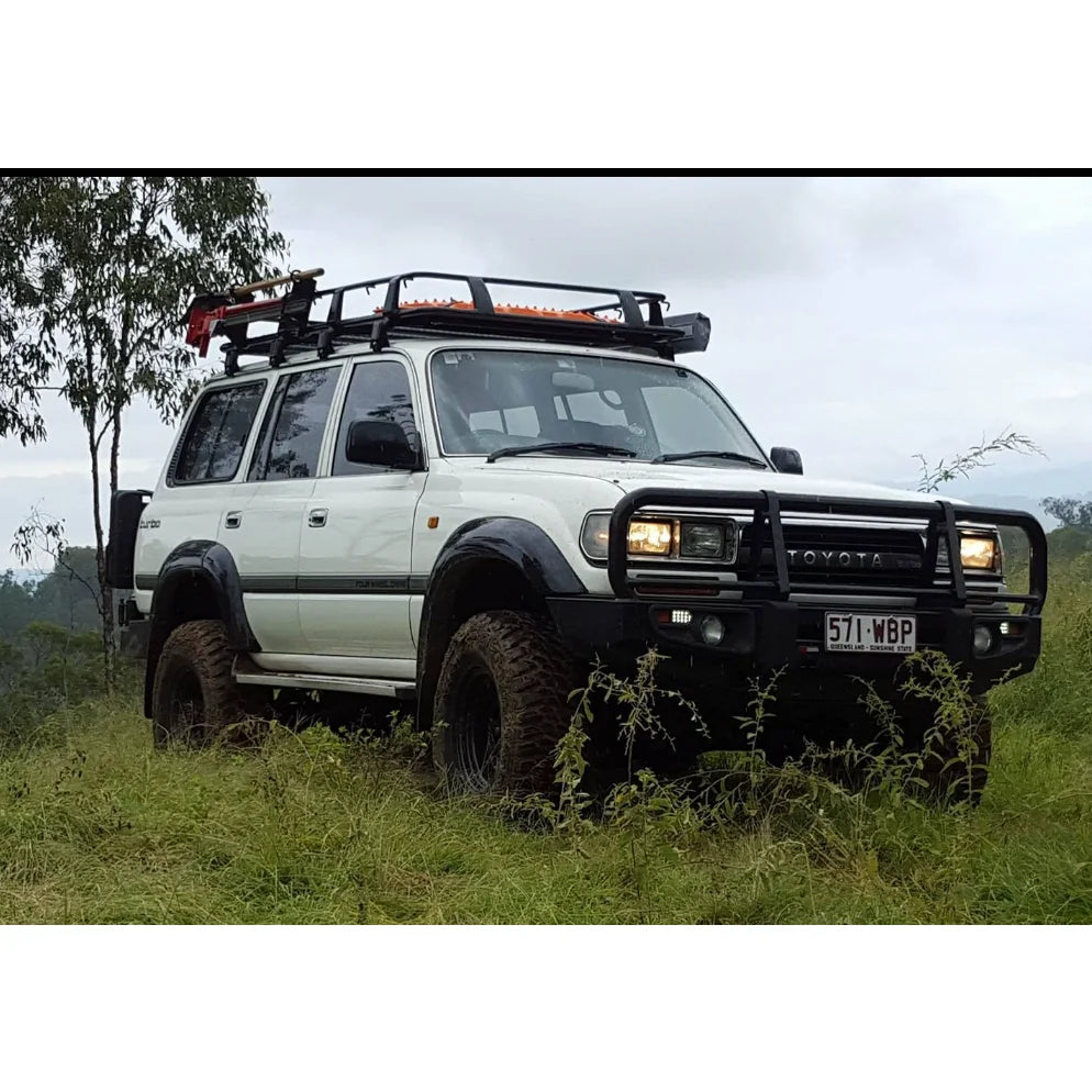 White toyota landcruiser fj80 with rockarmor steel rockslider checker plate side steps and roof rack visible from the side
