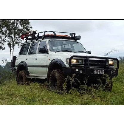 White toyota landcruiser fj80 with rockarmor steel rockslider checker plate side steps and roof rack visible from the side